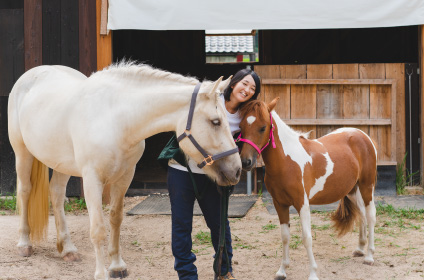 2頭の馬と戯れる笑顔の女性の写真