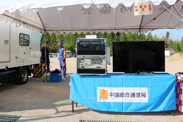 中国総合通信局所有の臨時災害放送局機器（机上左）を展示。災害時等に自治体に貸与。