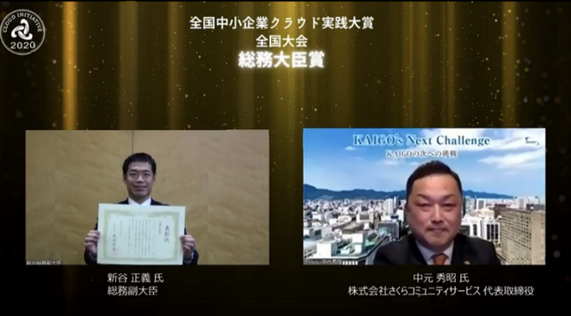 表彰式:(左)新谷総務副大臣と(右)さくらコミュニティサービス代表取締役 中元氏画像